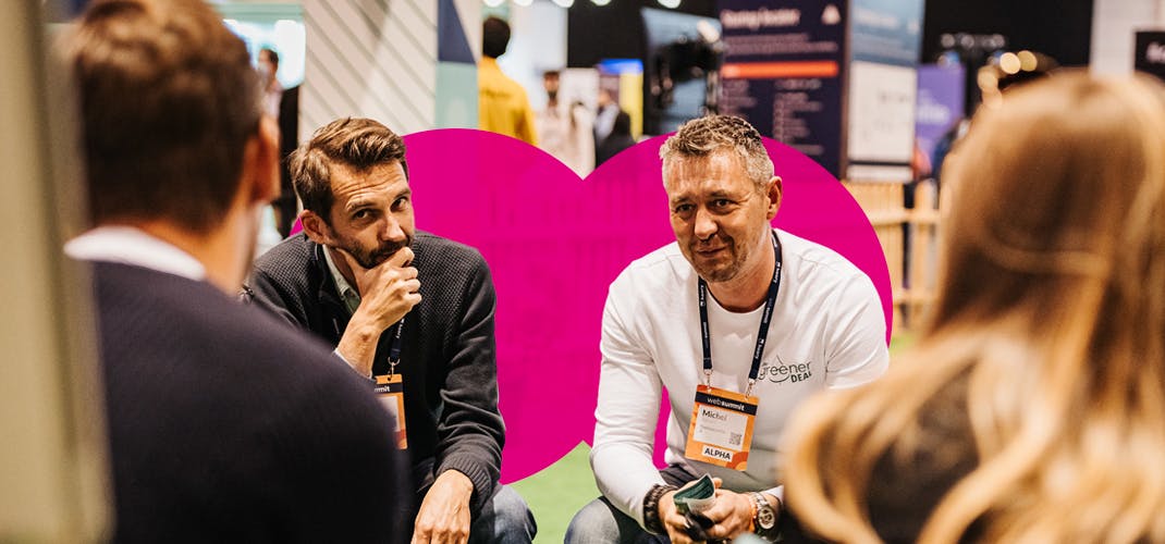 Two participants of Web Summit's Mentor Hours are seated and listening, facing other participants.