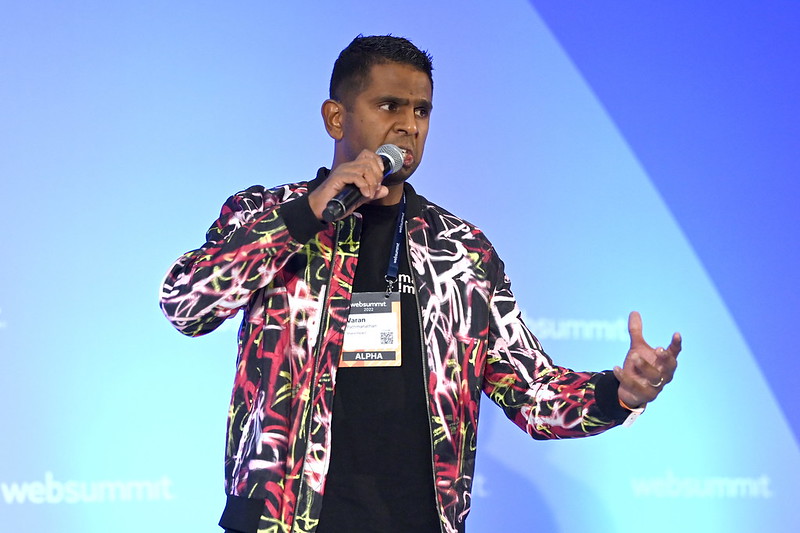 A person gestures emphatically while speaking into a hand-held microphone.